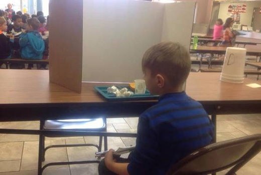 Učenik prvog razreda zbog kašnjenja jede užinu iza kartonske kutije.