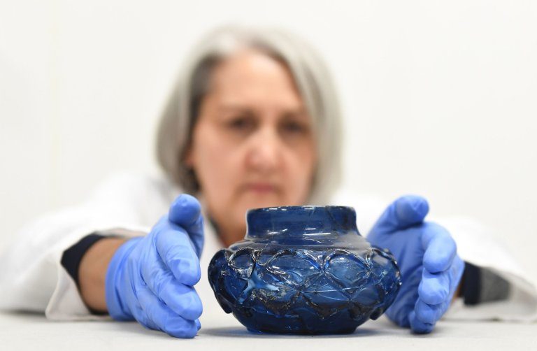 Konzervatorica Claire Reed pregledava uređenu plavu staklenu čašu koja je otkrivena u grobnoj