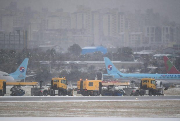Workers clear snow on runway at Jeju