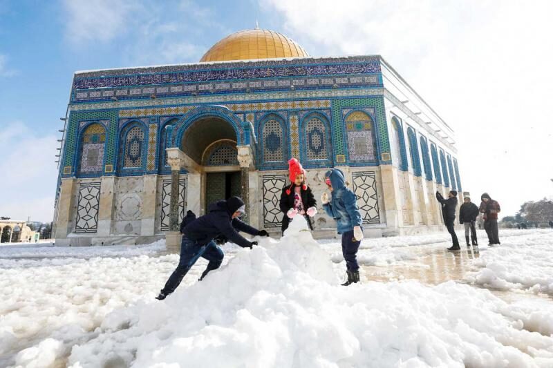 Children build a snowman in front of the Dome of the Rock, in Jerusalem’s Old City, January 27, 2022.