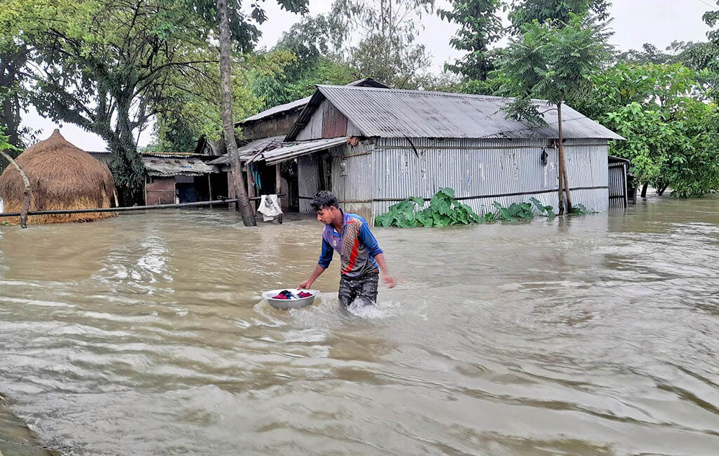 A man trudges through flood water in Gowainghat upazila of Sylhet on Thursday, June 16, 2022
