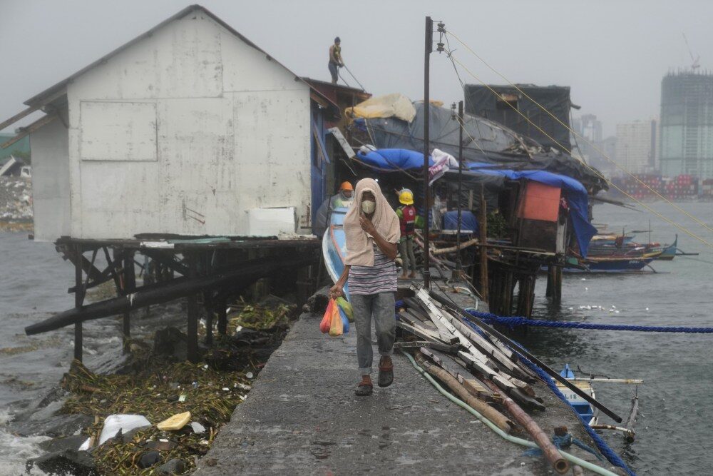 A man carries bags of food while another reinforces their roof as they prepare for the coming of Typhoon Noru in the Philippines capital Manila on Sunday.