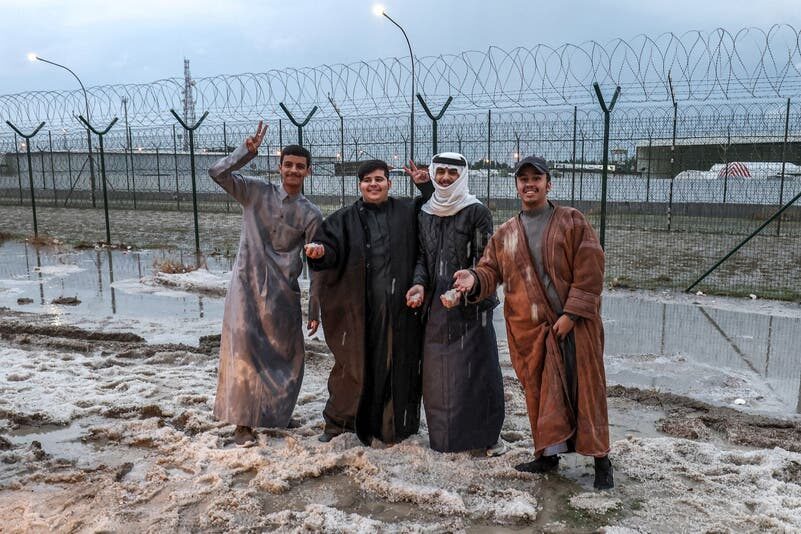 Klikni za povećanje Youths pose for a picture with hail particles along the side of a road after a storm in the Umm al-Haiman district, about 55 kilometres south of Kuwait City, on December 27, 2022.