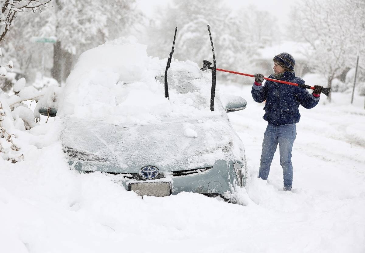 Cathy Morgan-Mace cleans snow and ice off her family's car during a snowstorm in Salt Lake City, Utah, on Wednesday, Feb. 22, 2023.