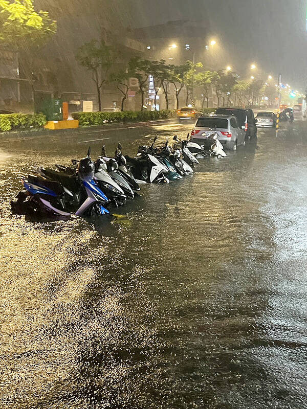 Motorcycles partly submerged in floodwaters are pictured on Nanshan Road in Taoyuan’s Lujhu District on Monday.
