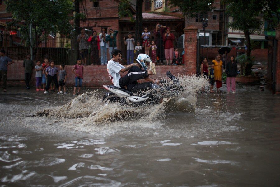 People ride motorcycle on a flooded street in Kathmandu, Nepal, July 23, 2023.