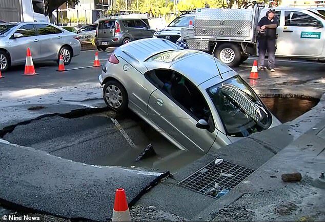 The silver two-door Peugeot went head first into the sinkhole