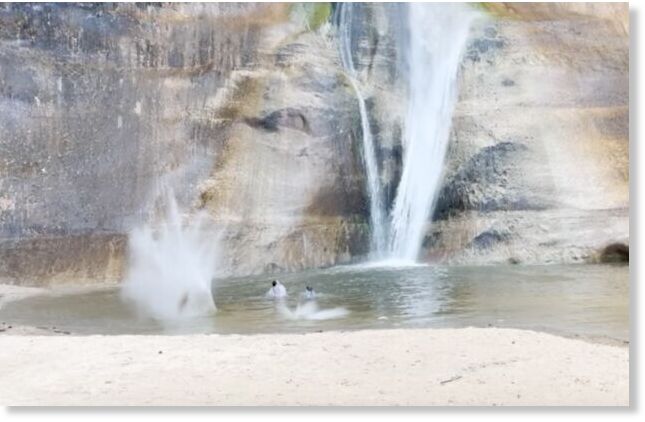 Large rocks falling near two visitors swimming near Lower Calf Creek Falls, Utah.