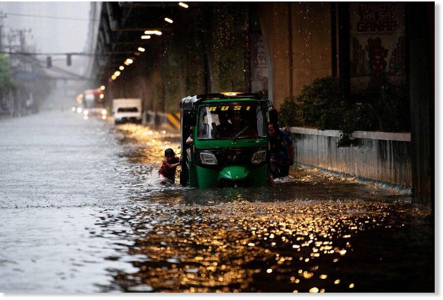 A boy helping to push a vehicle through a flooded street in Philippine capital Manila on July 22, after heavy rains caused floods.