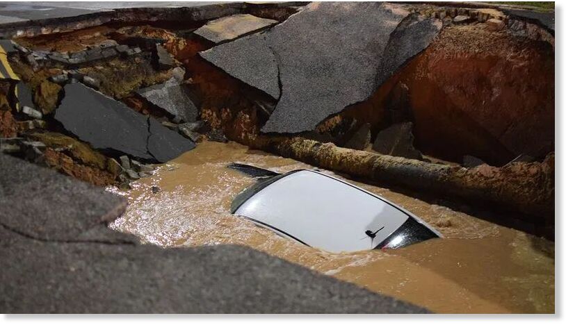Klikni za povećanje Water rushes over a car that has plunged into a sinkhole in east Baltimore.